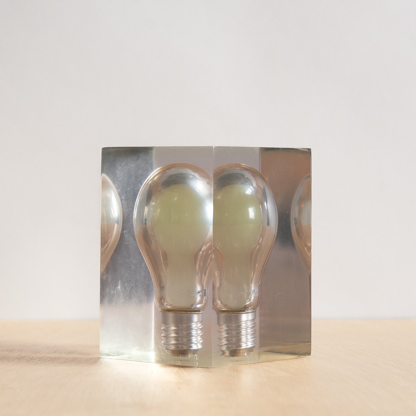light bulb in a clear acrylic box on a beige surface with a white background