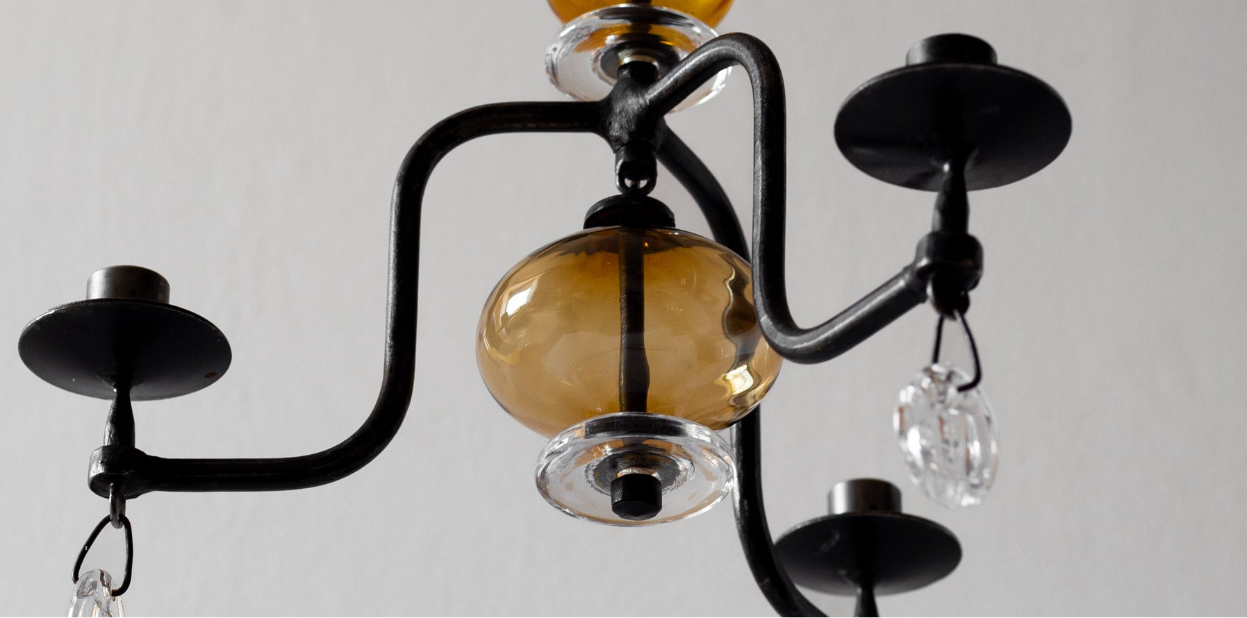 Chandelier with amber glass shades and black metal arms on a plain background