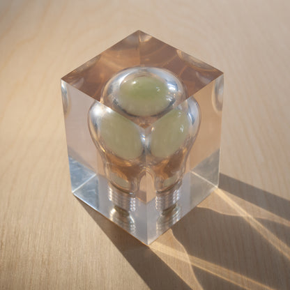 Clear crystal object with green spheres inside on a wooden surface