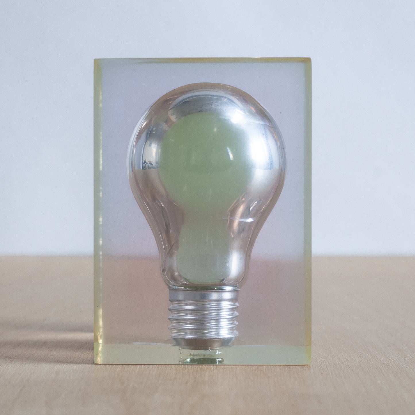 Clear light bulb in a plastic frame on a wooden surface with a white background