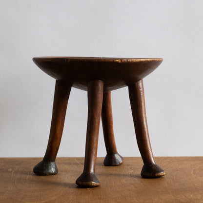 Wooden stool with four legs on a wooden surface and light gray background
