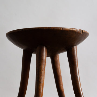 Wooden stool with four legs on a plain background