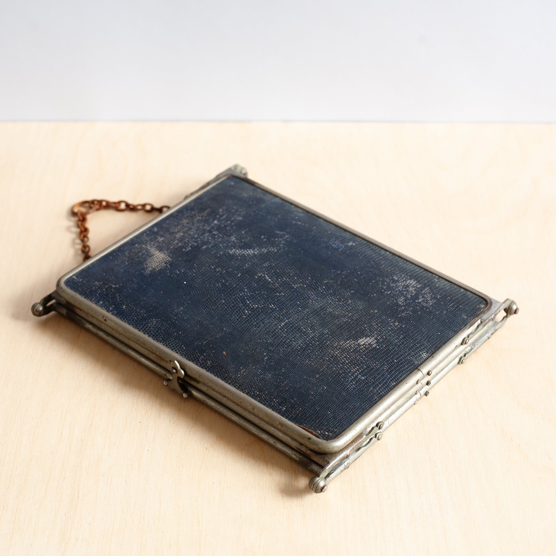 Vintage blue mirror with metal frame and chain on beige background