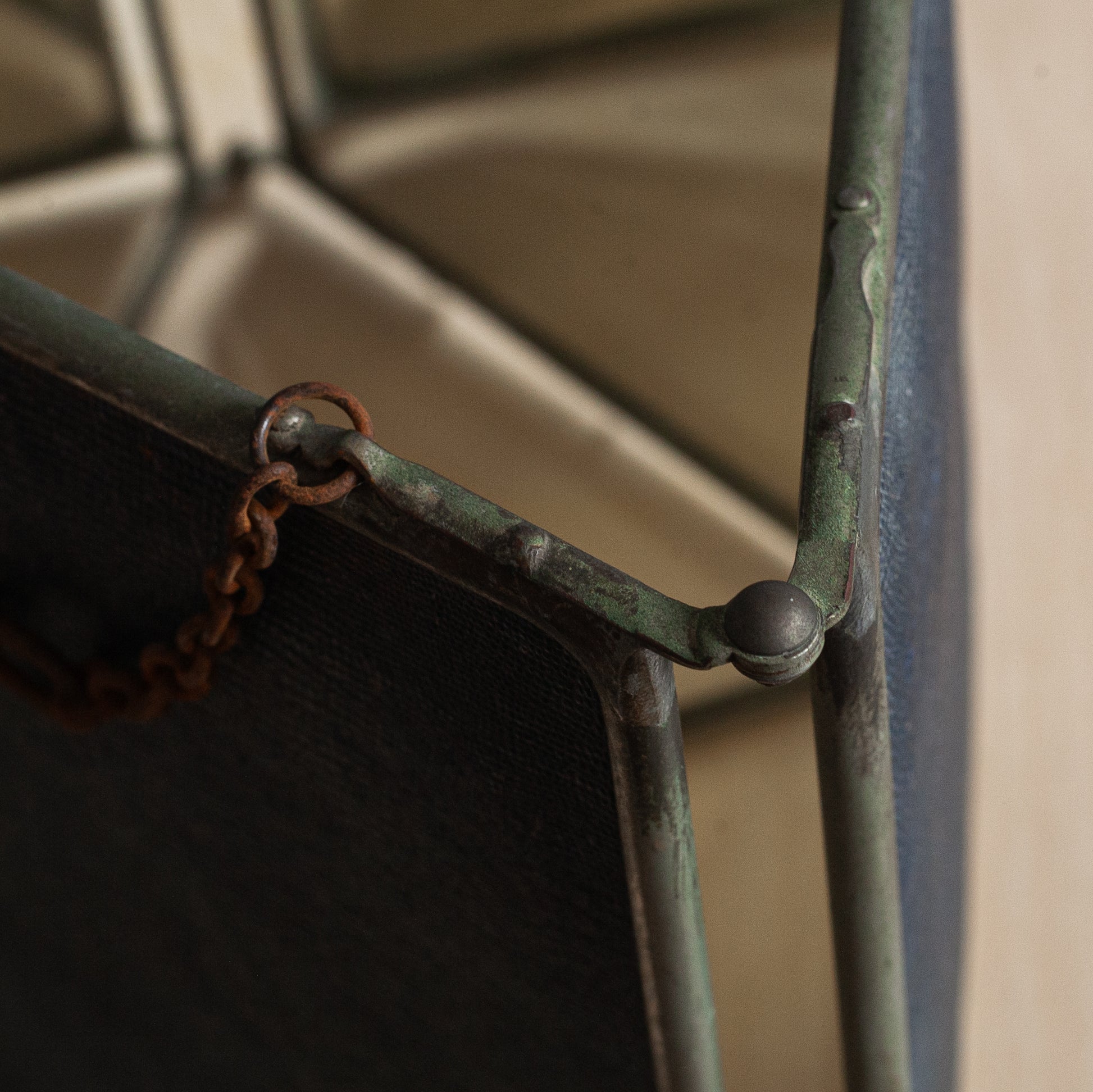 Close-up of a metal frame with a chain, showing signs of rust and wear.