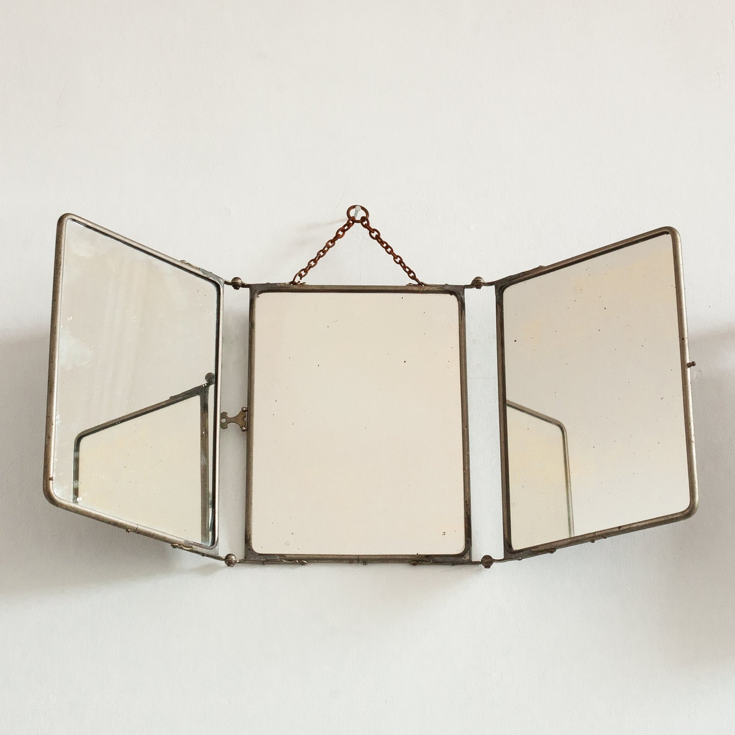Triptych wall-mounted mirror with brass frame on a white background