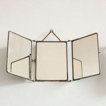 Triptych wall-mounted mirror with brass frame on a white background