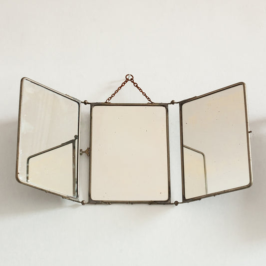 Triptych wall-mounted mirror with brass frame on a white background